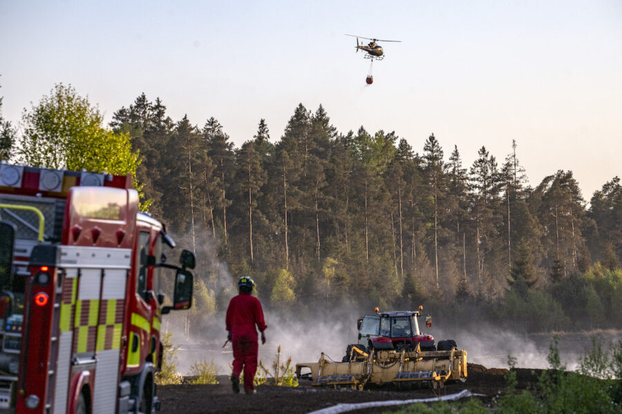 Helikoptrar vattenbombar skogen kring en torvtäkt i Kråkeryd utanför Hyltebruk vid en brand i maj 2025.
