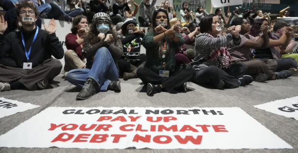 demonstranter sitter ner med banderoll