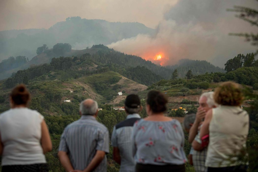 Residents observe smoke billowing from a forest fire raging near Montana Alta on the island of Gran Canaria on August 18, 2019. - Authorities on the Spanish island of Gran Canaria evacuated residents as a forest fire broke out just days after another blaze raged in the same area. (Photo by DESIREE MARTIN / AFP)