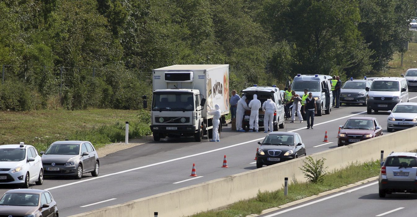 FILE - In this Aug. 27, 2015 file photo police stand near a truck that stands on the shoulder of the highway A4 near Parndorf south of Vienna, Austria. Various murder and smuggling charges will be recommended against one Afghan and seven Bulgarian suspects for the Aug. 2015 deaths of 71 migrants who suffocated in the back of a refrigerated truck, Hungarian police said Wednesday, Oct. 12, 2016. (AP Photo/Ronald Zak)