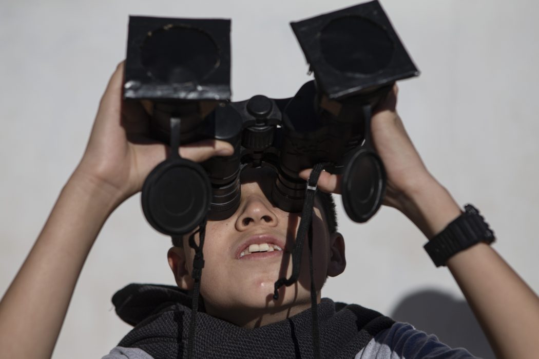 A youth tests special binoculars to view tomorrow's total solar eclipse near Central Park in La Higuera, Chile, Monday, July 1, 2019. Tourists and scientists will gather in northern Chile, one of the best places in the world to watch the next the eclipse that will plunge parts of South America into darkness. (AP Photo/Esteban Felix)