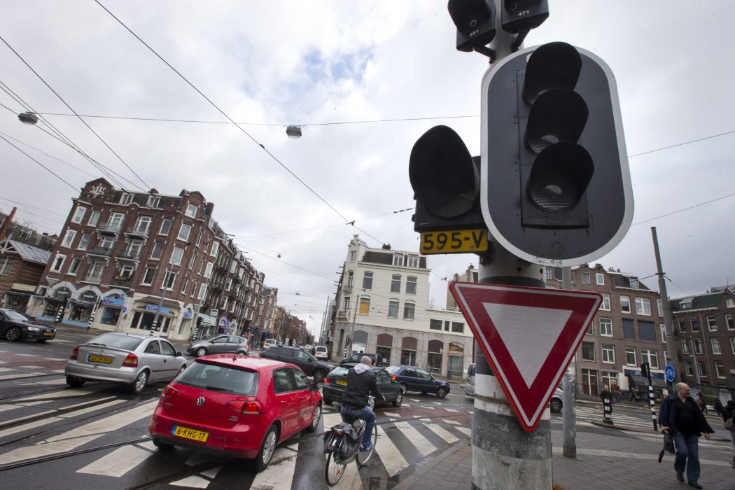 Cars and bicycles improvise crossing an intersection as traffic lights are off during a power outage in Amsterdam, Netherlands, Friday, March 27, 2015. The Dutch capital Amsterdam and surrounding towns suffered a major power outage, halting trains, trams and affecting flights to Schiphol Airport.(AP Photo/Peter Dejong)