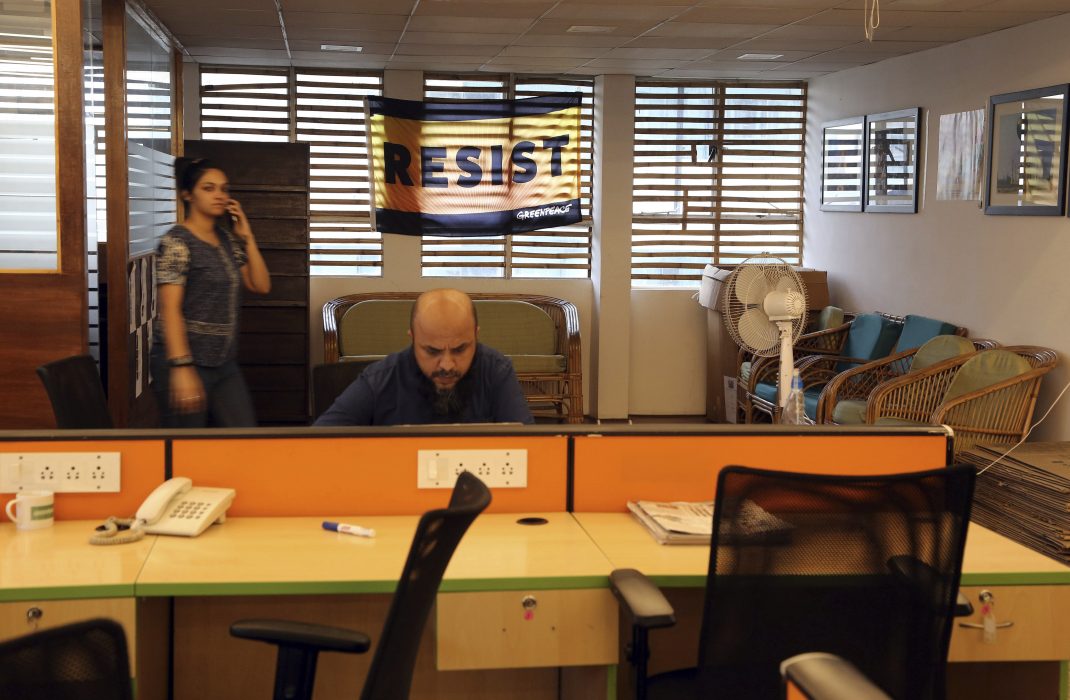 A banner is displayed on a window as an employee works at Greenpeace India office in Bangalore, India, Tuesday, Feb. 5, 2019. International rights groups and foreign aid organizations with deep roots in India say they are struggling to operate under the administration of Prime Minister Narendra Modi, whose Hindu nationalist Bharatiya Janata Party has elevated the role of homegrown social groups while cracking down on foreign charities. (AP Photo/Aijaz Rahi)