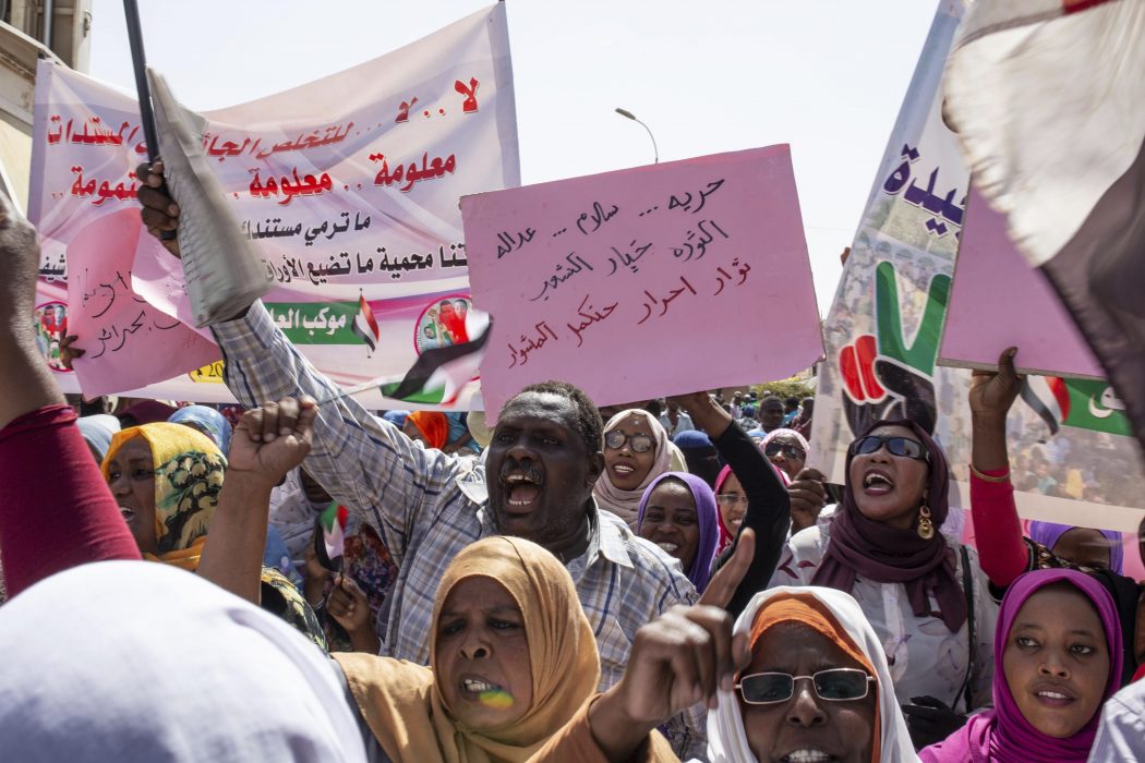 Protesters carry posters in Arabic that say, "Freedom, justice, and peace, and the revolution is the choice of the people," at the sit-in outside the military headquarters, in Khartoum, Sudan, Thursday, May 2, 2019. Sudan's protesters are holding a mass rally to step up pressure on the military to hand power to civilians following last month's overthrow of President Omar al-Bashir. (AP Photos/Salih Basheer)