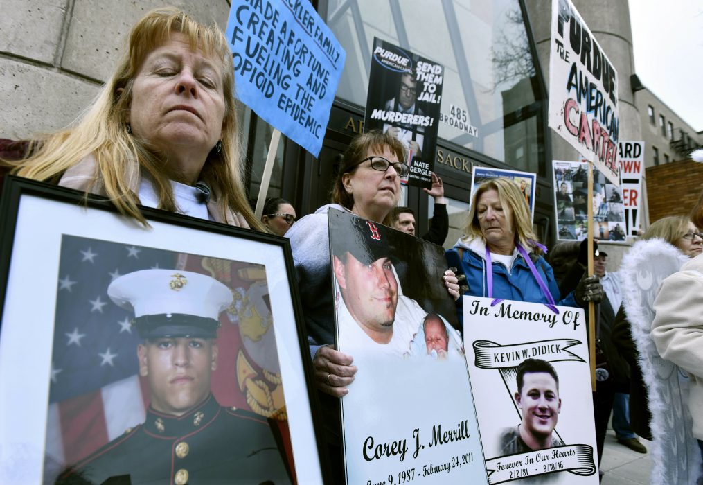 Kathleen Scarpone, left, of Kingston, N.H., and Cheryl Juaire, second from left, of Marlborough, Mass., protest in front of the Arthur M. Sackler Museum at Harvard University, Friday, April 12, 2019, in Cambridge, Mass. Juaire, who's son Corey Merrill died of in 2011, led a demonstration by parents who have lost a child to opioid abuse, campaigning for the removal of the Sackler family name from the building at Harvard. (AP Photo/Josh Reynolds)