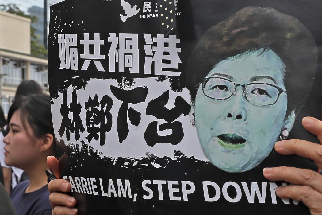 In this Monday, June 17, 2019, photo, a protester holds a placard baring an image of Hong Kong Chief Executive Carrie Lam as they gather near the Legislative Council to continue protest against the unpopular extradition bill in Hong Kong. The various pro-democracy groups that helped drive and organize the protests are pushing for LamÄôs resignation and the permanent scrapping of what they call the ÄúevilÄù extradition bill. (AP Photo/Kin Cheung)