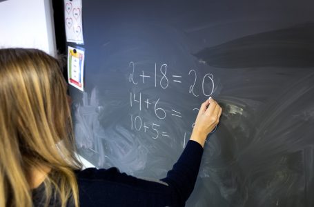 Lærer som skriver på tavle på barneskole.